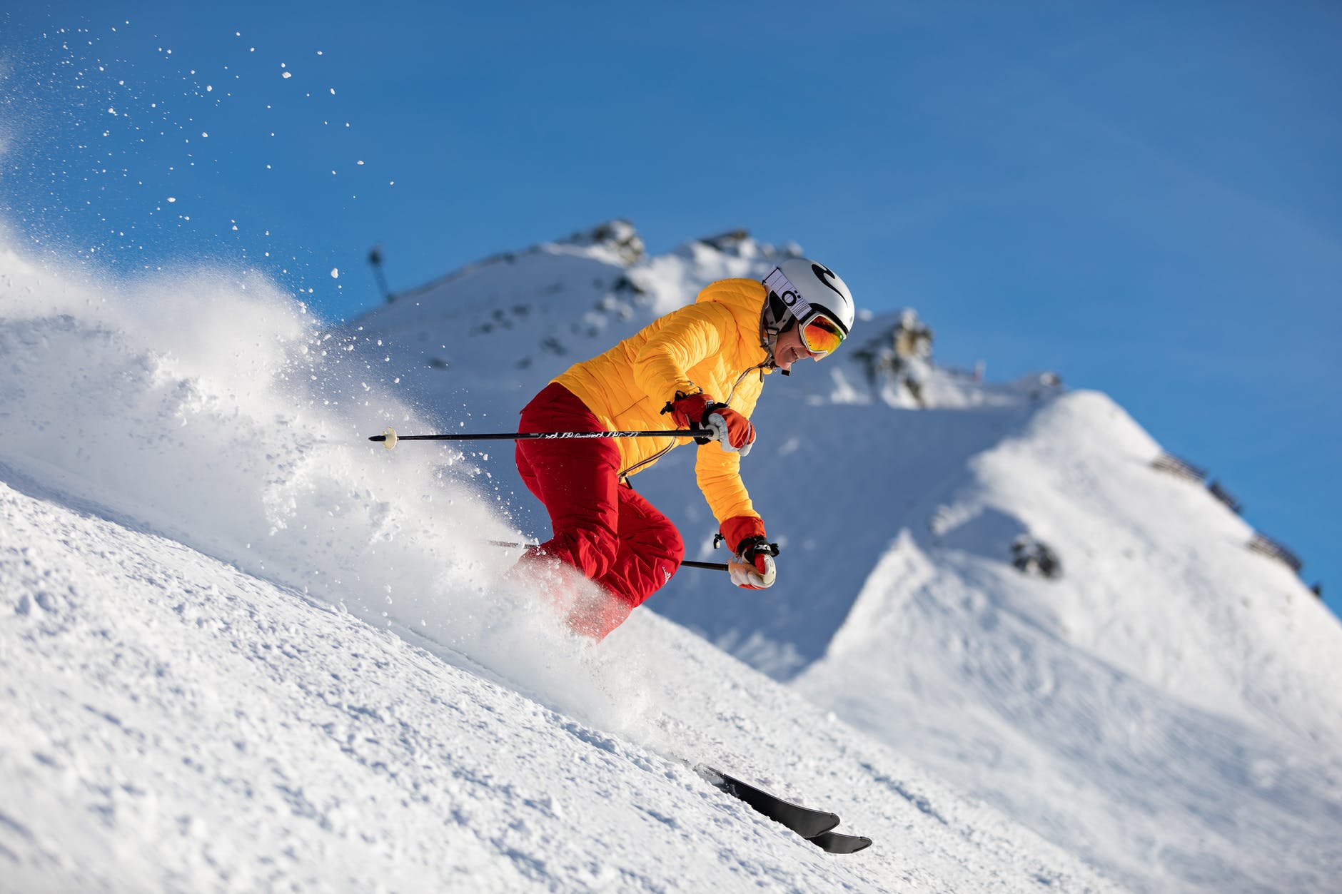 person in yellow jacket and red pants skiing